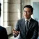 young man, business suit, glasses, discussion, gesturing, office, communication, man in suit, speaking, professional, business, manager, indoor, formal, meeting, talking person, concentration, asian features, young professional, work conversation, work environment